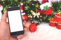 Mockup image of a hand holding black mobile phone with blank white screen with christmas decorations Royalty Free Stock Photo