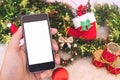 Mockup image of a hand holding black mobile phone with blank white screen with christmas decorations Royalty Free Stock Photo