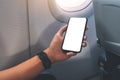 A hand holding a black smart phone with blank desktop screen next to an airplane window Royalty Free Stock Photo