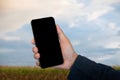 Mockup image of hand holding blank  mobile phone with blank white screen in field, panorama with copy space Royalty Free Stock Photo