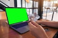 Mockup image of a hand holding credit cards while using and typing on laptop with blank green screen on wooden table Royalty Free Stock Photo