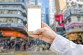 Mockup image of hand holding gold mobile phone and blurred city Royalty Free Stock Photo