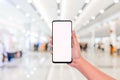 Mockup image of hand holding mobile phone with blank white screen with blur office corridor hall way background bokeh light,White