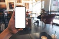 A hand holding and showing black mobile phone with blank white screen in cafe Royalty Free Stock Photo