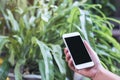 Mockup image of a hand holding and using white smart phone with blank black screen in outdoor Royalty Free Stock Photo