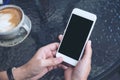 Mockup image of a hand holding white mobile phone with blank black screen and coffee cup Royalty Free Stock Photo