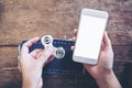 Mockup image of a hand holding white mobile phone with blank screen and playing fidget spinner Royalty Free Stock Photo