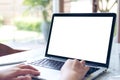 Hand using laptop with blank white screen on vintage wooden table in cafe Royalty Free Stock Photo