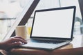 Hand using laptop with blank white screen on vintage wooden table in cafe Royalty Free Stock Photo