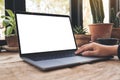 Mockup image of hand using and typing on laptop with blank white desktop screen on vintage wooden table Royalty Free Stock Photo
