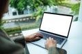 A hand using and typing on laptop computer keyboard with blank white desktop screen in office Royalty Free Stock Photo