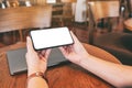 Hands holding black mobile phone with blank desktop screen with laptop computer on the table Royalty Free Stock Photo