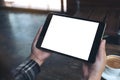 Hands holding black tablet pc with white blank screen and coffee cup on table background Royalty Free Stock Photo