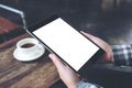 Hands holding black tablet pc with white blank screen and coffee cup on table background Royalty Free Stock Photo