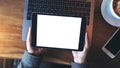 Mockup image of hands holding black tablet pc with white blank screen and laptop , coffee cup on wooden table background Royalty Free Stock Photo