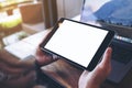 Mockup image of hands holding black tablet pc with white blank screen and laptop on wooden table background Royalty Free Stock Photo