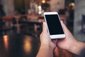 Hands holding white mobile phone with blank black screen in vintage cafe Royalty Free Stock Photo