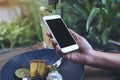 Mockup image of hands holding white mobile phone with blank black screen while eating yellow lemon curd cake on wooden table Royalty Free Stock Photo