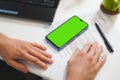Mockup image, man hands near blank green screen mobile smart phone, working on laptop Royalty Free Stock Photo