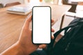 A man`s hand holding and showing black mobile phone with blank white screen while sitting in cafe Royalty Free Stock Photo