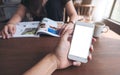 Mockup image of a man`s hand holding and using white smart phone with blank screen on wooden table and green nature Royalty Free Stock Photo