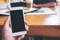 Mockup image of a man`s hand holding white mobile phone with blank black screen in modern cafe Royalty Free Stock Photo