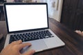 A man`s hand using laptop with blank white screen on vintage wooden table in cafe Royalty Free Stock Photo