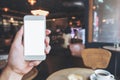 Man`s hands holding mobile phone with blank black desktop screen in cafe Royalty Free Stock Photo