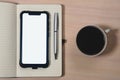 Mockup image of a smartphone with the blank white screen, pen, notebook and a cup of coffee on a wooden table Royalty Free Stock Photo