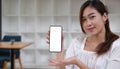 Mockup image of a smiley Asian beautiful woman holding and showing black mobile phone with blank white screen. Royalty Free Stock Photo