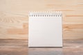 Mockup image. square notebook with blank page stands upright on wood table against a wooden wall background. Blank sketchbook mock