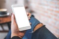 Mockup image of a woma`s hand holding white mobile phone with blank desktop screen on thigh