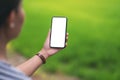 A woman holding black mobile phone with blank desktop screen with blur green nature background Royalty Free Stock Photo