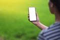 A woman holding black mobile phone with blank desktop screen with blur green nature background Royalty Free Stock Photo