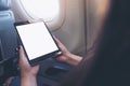 Mockup image of a woman holding and looking at black tablet pc with blank white desktop screen next to an airplane window Royalty Free Stock Photo