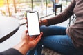 a woman holding and showing white mobile phone with blank black desktop screen to her friend Royalty Free Stock Photo