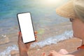 Woman hand holding mobile phone with blank white screen mockup on the beach. Cell mobile phone in woman hand for mockup. Sea Beach