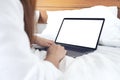 Mockup image of a woman lying on a bed , using and typing on laptop with blank white desktop screen Royalty Free Stock Photo