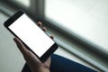 Mockup image of woman`s hand holding black mobile phone with blank white screen on thigh with white tile floor