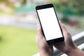 Mockup image of a woman`s hand holding and using black smart phone with blank white screen while standing at the balcony Royalty Free Stock Photo