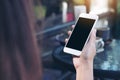 Mockup image of a woman`s hand holding white mobile phone with blank black desktop screen and coffee cup Royalty Free Stock Photo