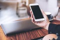 Mockup image of a woman`s hand holding white mobile phone with blank black desktop screen Royalty Free Stock Photo