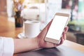 Mockup image of a woman`s hand holding white mobile phone with blank desktop screen and coffee cup Royalty Free Stock Photo