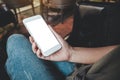 A woman`s hand holding white mobile phone with blank desktop screen on thigh while sitting in cafe Royalty Free Stock Photo