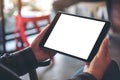 Woman`s hands holding black tablet pc with blank screen horizontally in cafe Royalty Free Stock Photo