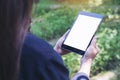 Mockup image of woman`s hands holding black tablet pc with blank white desktop screen and green nature Royalty Free Stock Photo