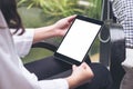 Woman`s hands holding black tablet pc with blank white desktop screen and green nature background Royalty Free Stock Photo