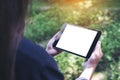 Mockup image of woman`s hands holding black tablet pc with blank white desktop screen and green nature Royalty Free Stock Photo