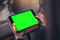 Mockup image of woman`s hands holding and looking at black tablet pc with blank green desktop screen Royalty Free Stock Photo