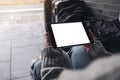 Woman`s hands holding and using black tablet pc with blank white desktop screen while sitting on the floor with baggages